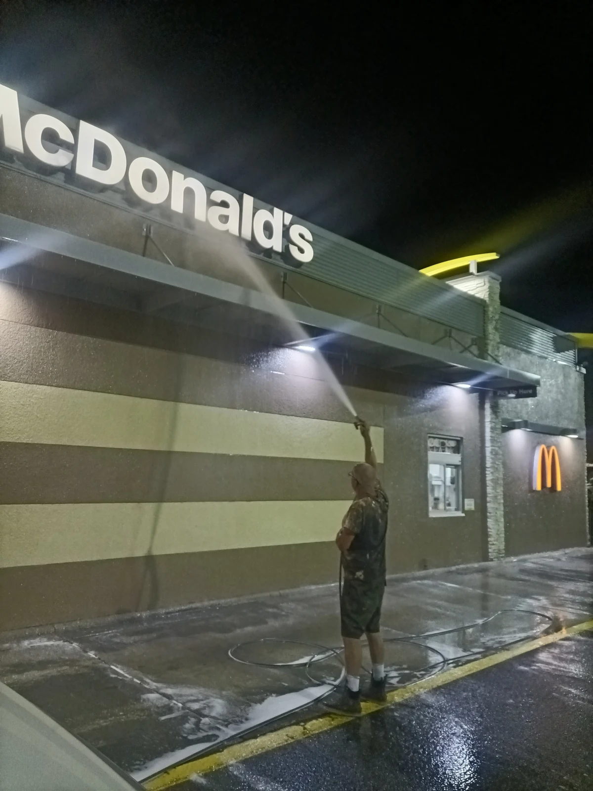 Safe Touch worker washing the McDonald's exterior and awning at night