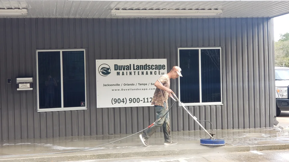 Safe Touch operator cleaning the concrete sidewalk outside a commercial building with a blue surface cleaner