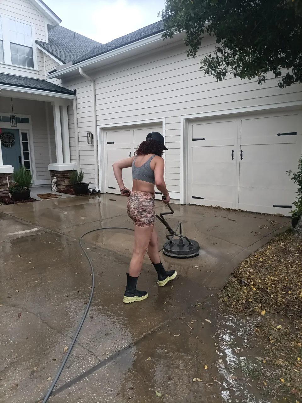 Safe Touch technician using a circular surface cleaner on a residential concrete driveway