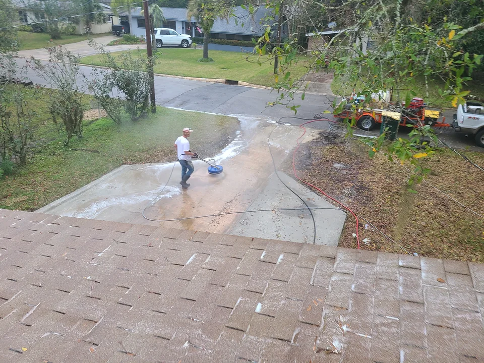 Overhead view of a Safe Touch crew surface-cleaning a concrete driveway with the wash rig parked nearby