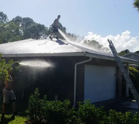 Safe Touch crew washing a residential shingle roof and rinsing below the gutters