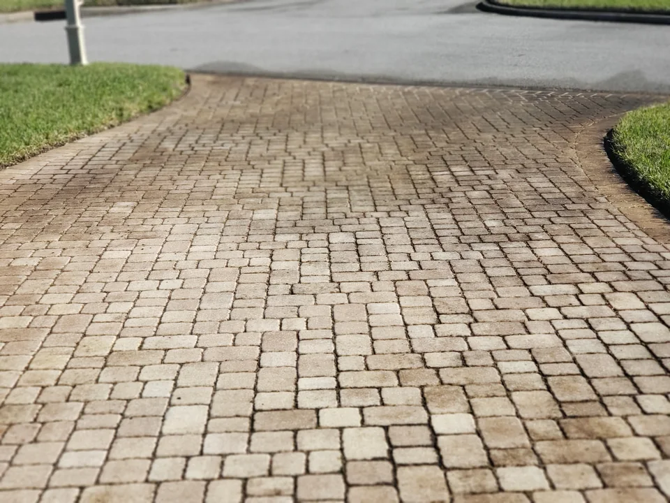 Paver driveway before cleaning with discoloration across the blocks and joints