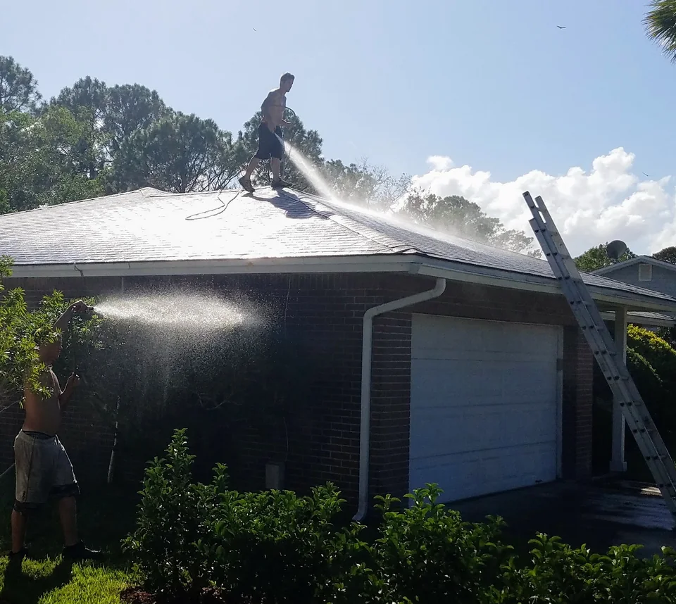 Safe Touch crew washing a residential shingle roof while a second technician rinses below the gutters
