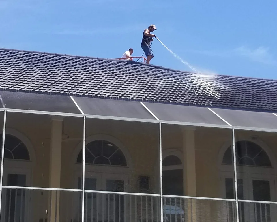 Safe Touch crew cleaning a tile roof above a screened patio